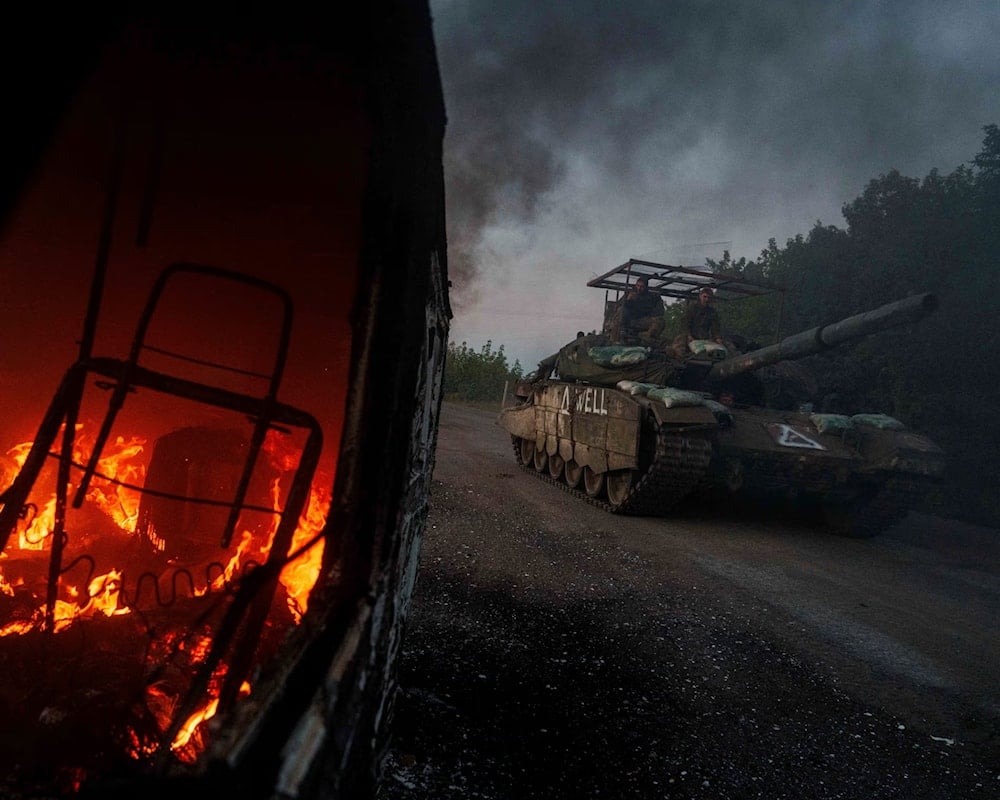 A Ukrainian tank passes by a burning car near the Russian-Ukrainian border in the Sumy region of Ukraine (Evgeniy Maloletka/AP)
