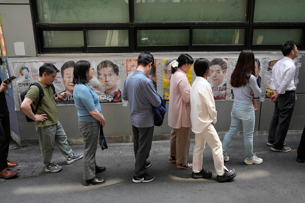 People wait in line by posters of presidential candidates as they wait to cast their early votes for the June 3 presidential election near a polling station in Seoul, South Korea, Thursday, May 29, 2025. (AP)