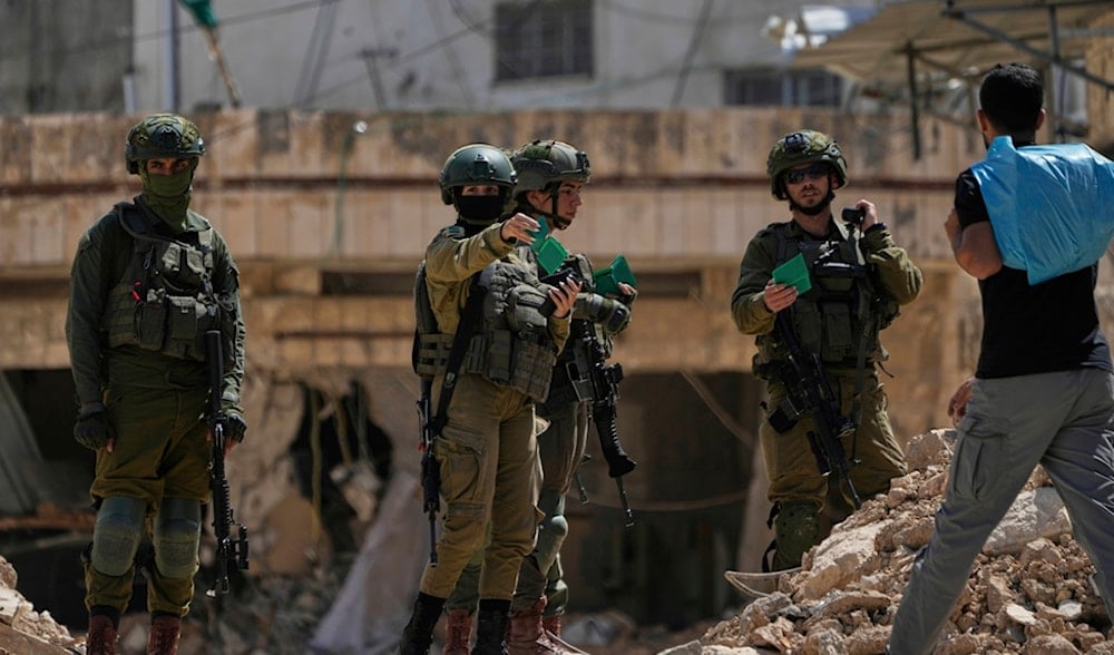 Israeli soldiers check the identification cards of residents of the now-displaced Palestinian refugee camp of Tulkarm, Thursday, May 29, 2025. (AP)