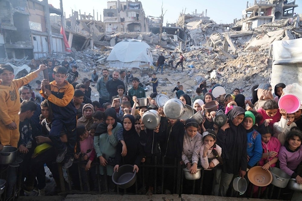 Palestinians wait for donated food at a distribution center in Beit Lahiya, northern Gaza Strip, Sunday, March 16, 2025 (AP)