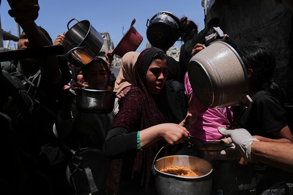 Palestinians receive donated food at a community kitchen in Beit Lahia, northern Gaza Strip, Saturday, May 3, 2025 (AP)