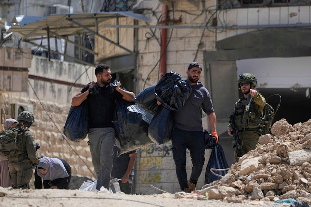 Israeli soldiers check the identification cards of residents of the now evacuated Palestinian refugee camp of Tulkarm before the destruction of their homes in the occupied West Bank city of Tulkarm, Thursday, May 29, 2025 (AP)