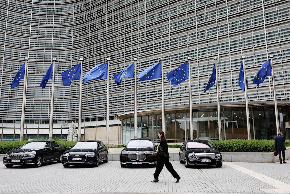 European Union flags flap in the wind as a woman walks past diplomatic vehicles outside of EU headquarters in Brussels, Belgium, Tuesday, May 27, 2025. (AP)