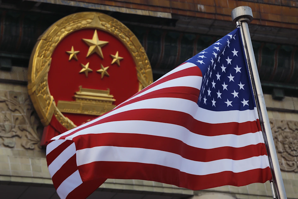 An American flag is flown next to the Chinese national emblem outside the Great Hall of the People in Beijing, November 9, 2017 (AP/Andy Wong)