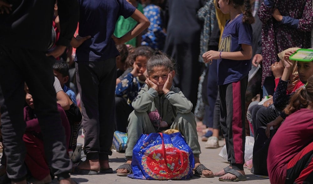 A Palestinian girl waits to collect donated food at a food distribution kitchen in Deir al-Balah, Gaza Strip, Friday, May 30, 2025. (AP)