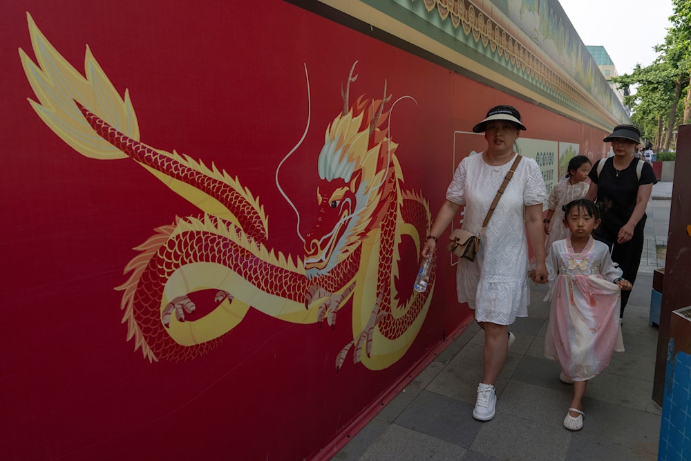 Tourists walk past a mural depicting a Chinese dragon along along the Wangfujing mall street in Beijing, Wednesday, June 19, 2024. (AP)