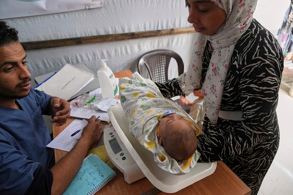 Doctors weigh a Palestinian baby at the Médecins Sans Frontières (MSF) clinic in Muwasi, near Khan Younis in the southern Gaza Strip, Tuesday, April 8, 2025 (AP)