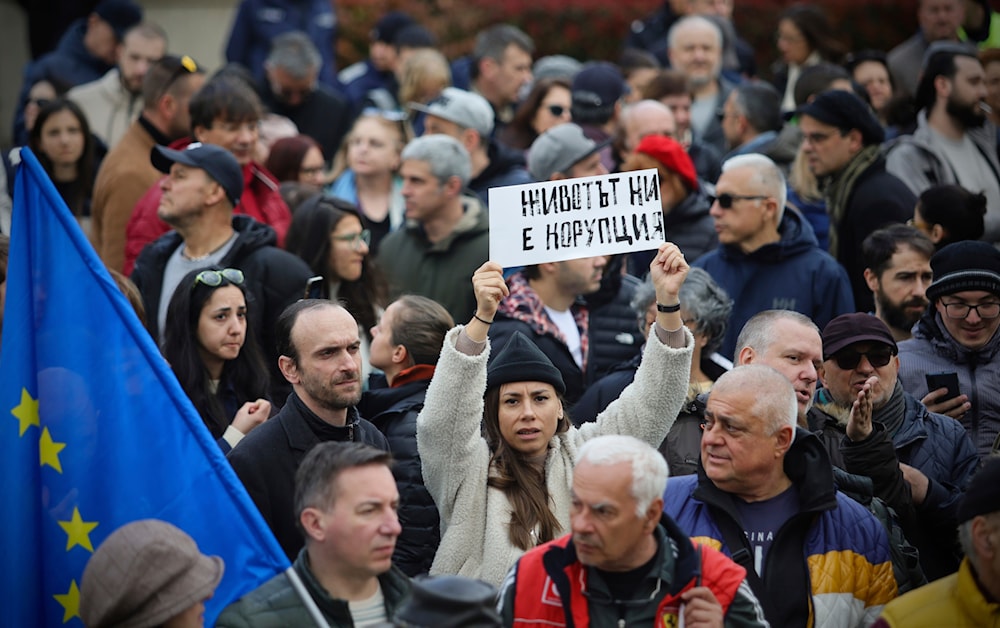 A demonstrator holds a sign that reads in Bulgarian 