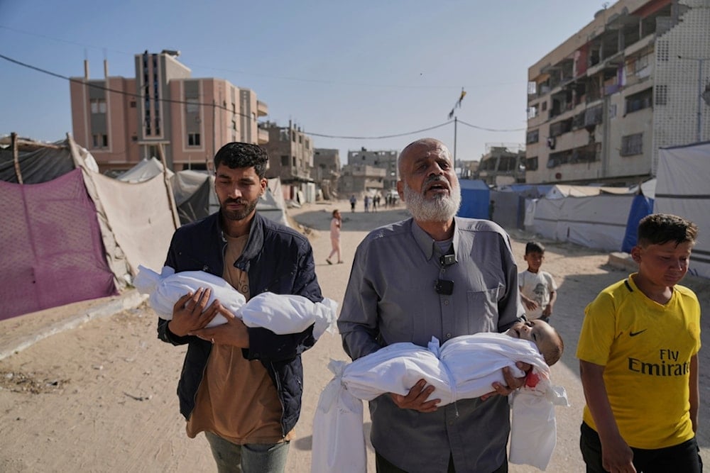 Abdel Rahman Sinwar, left, carries the body of his infant son while the child's grandfather carries the body of his one-year-old grandson, both killed in an Israeli army strike in Khan Younis, Gaza Strip, on Saturday, May 3, 2025 (AP)