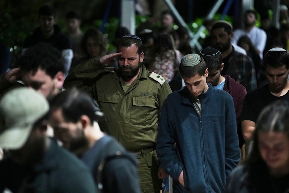People stand still to observe a minute of silence as a siren sound marks the beginning of the Israeli annual Memorial Day for the fallen soldiers at Mount Herzl military cemetery in al-Quds, occupied Palestine, Tuesday, April 29, 2025 (AP)