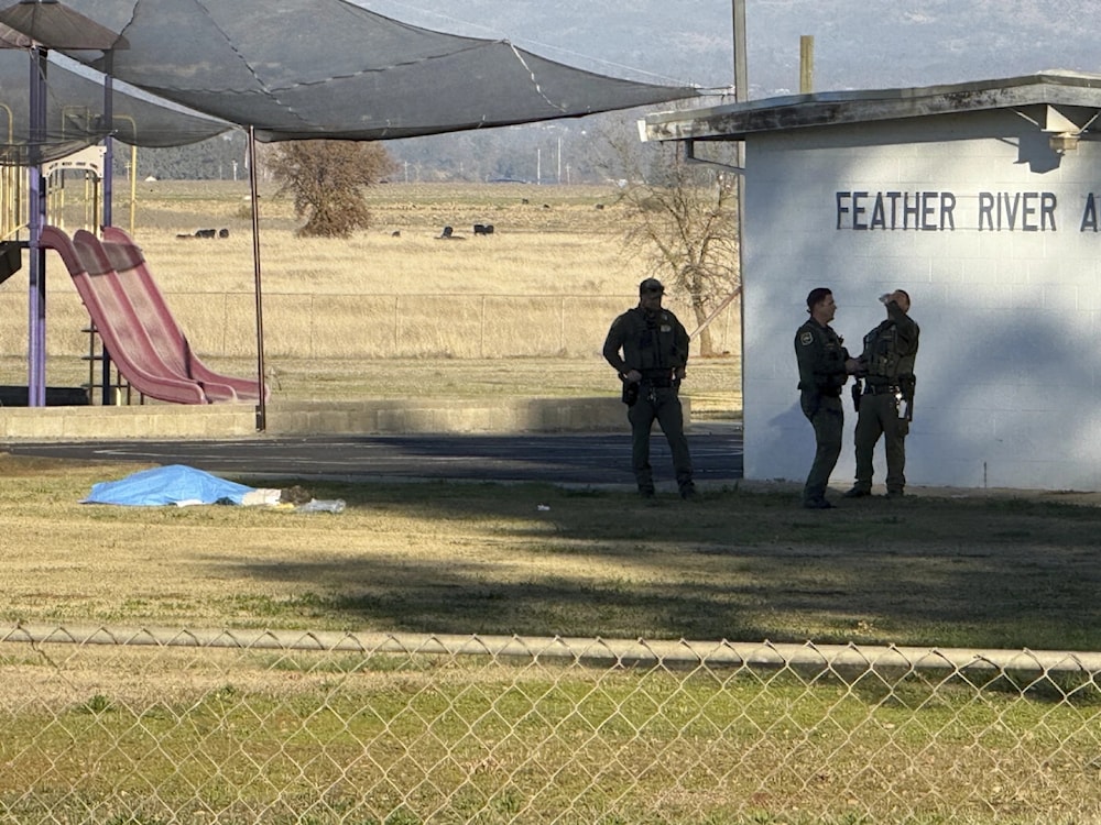 Police officers stand near a body covered by a tarp outside of Feather River Adventist School after a shooting December 4, 2024, in Oroville, California (Michael Weber/The Chico Enterprise-Record via AP)