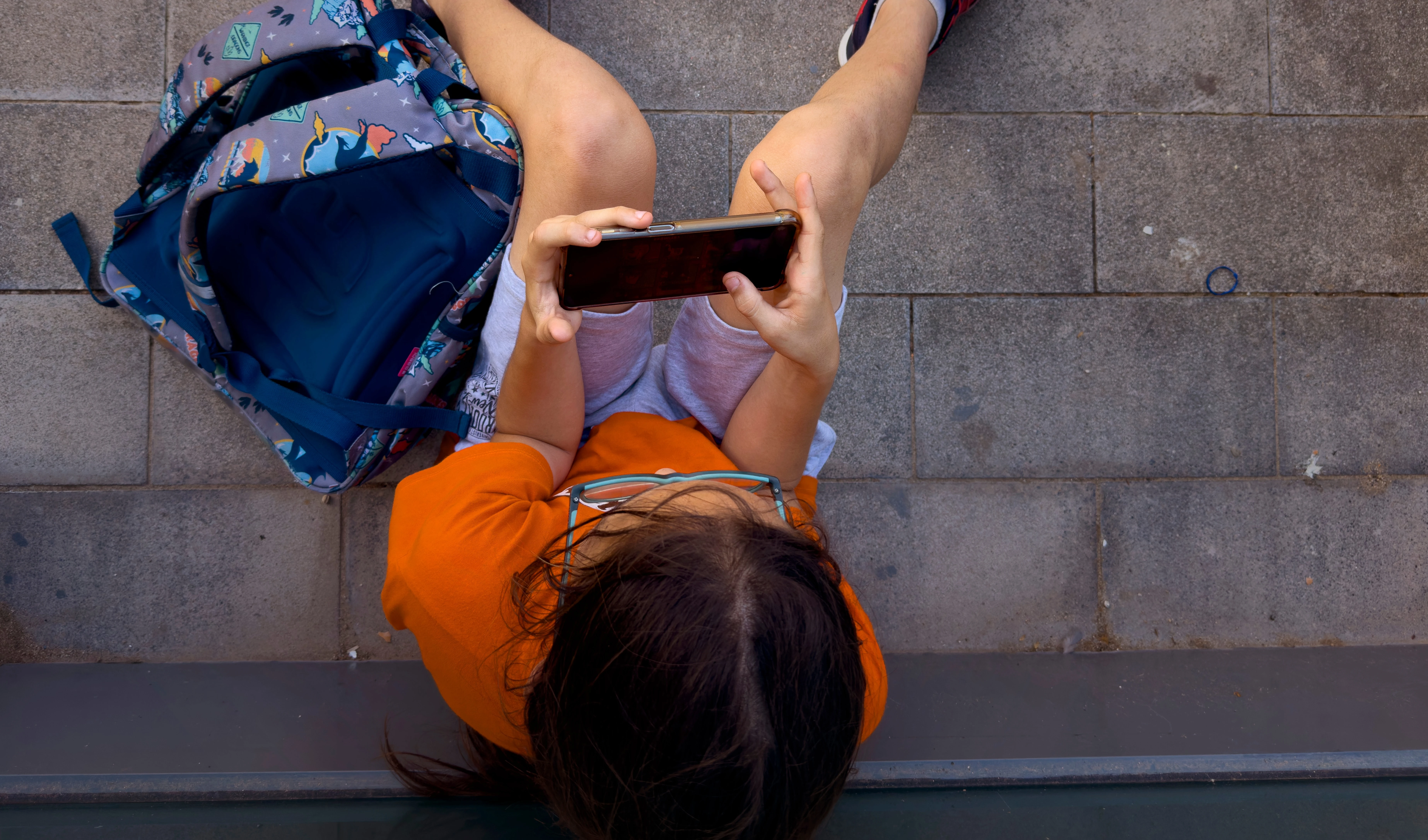 A 12-year-old boy plays with his personal phone outside school in Barcelona, Spain, Monday, June 17, 2024. (AP)