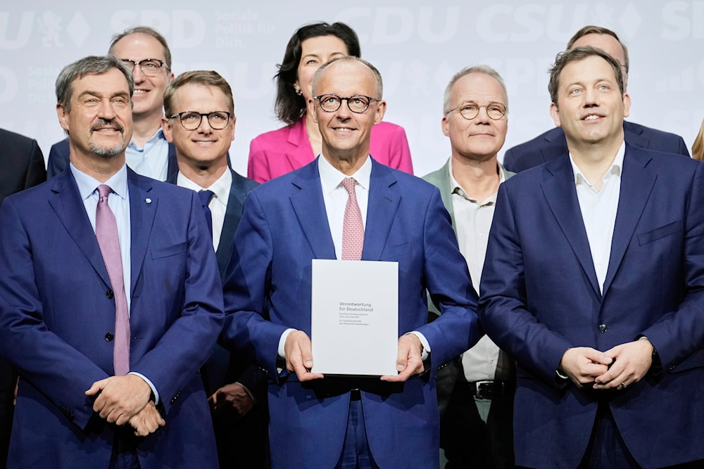 CSU leader Markus Soeder, CDU leader Friedrich Merz, and SPD leader Lars Klingbeil, front row from left, stand together with the new ministers after signing the coalition treaty in Berlin, Germany, Monday, May 5, 2025. (AP Photo/Ebrahim Noroozi)