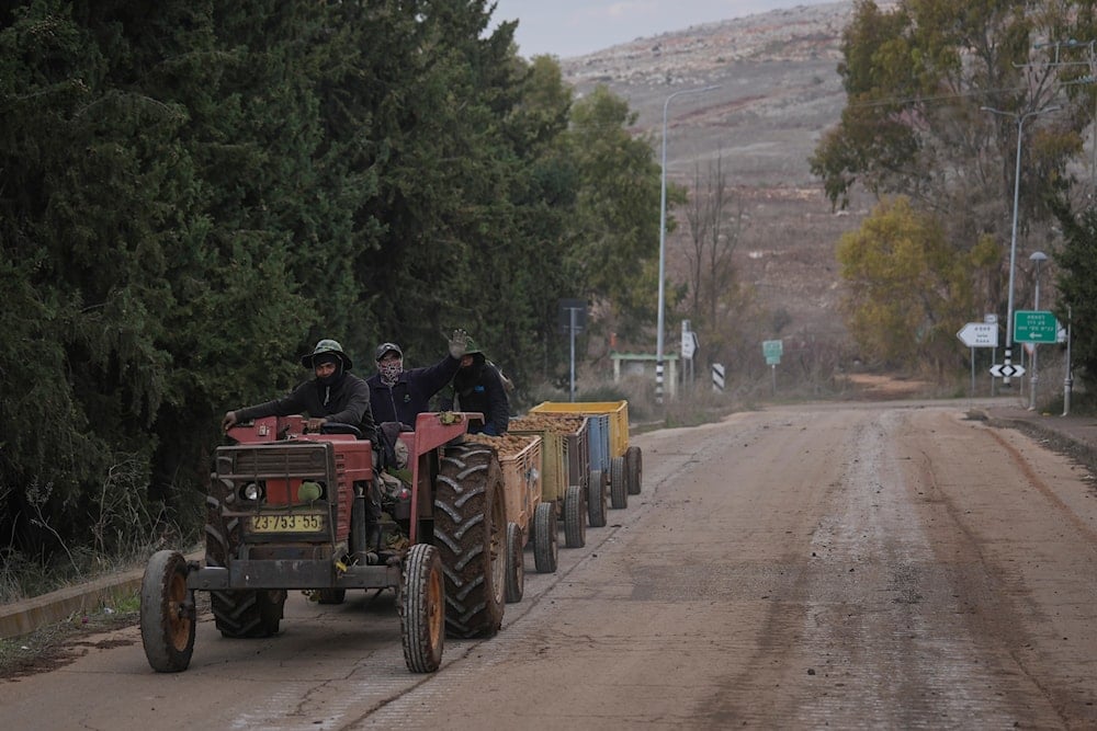 Foreign workers ride a tractor outside the agricultural settlement of Avivim, next to the Lebanese border in upper Galilee, Occupied Palestine, Thursday Nov 28, 2024 (AP)