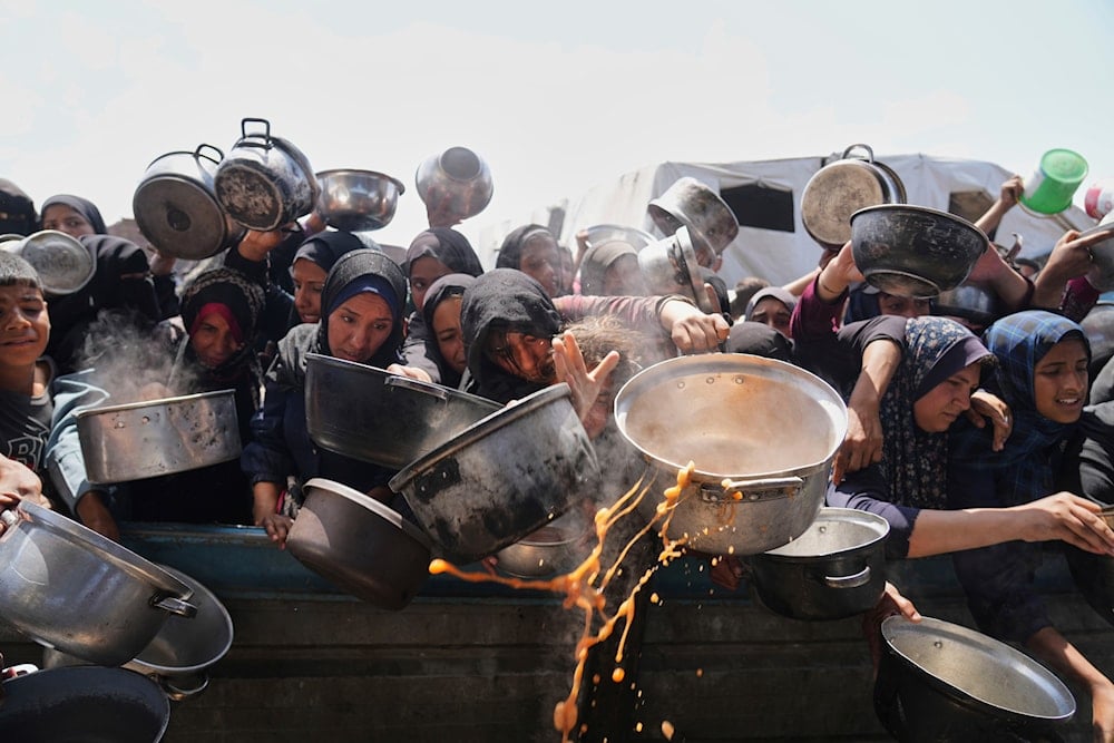 Palestinians struggle to get donated food at a community kitchen in Khan Younis, Gaza Strip, Monday, May 5, 2025 (AP)