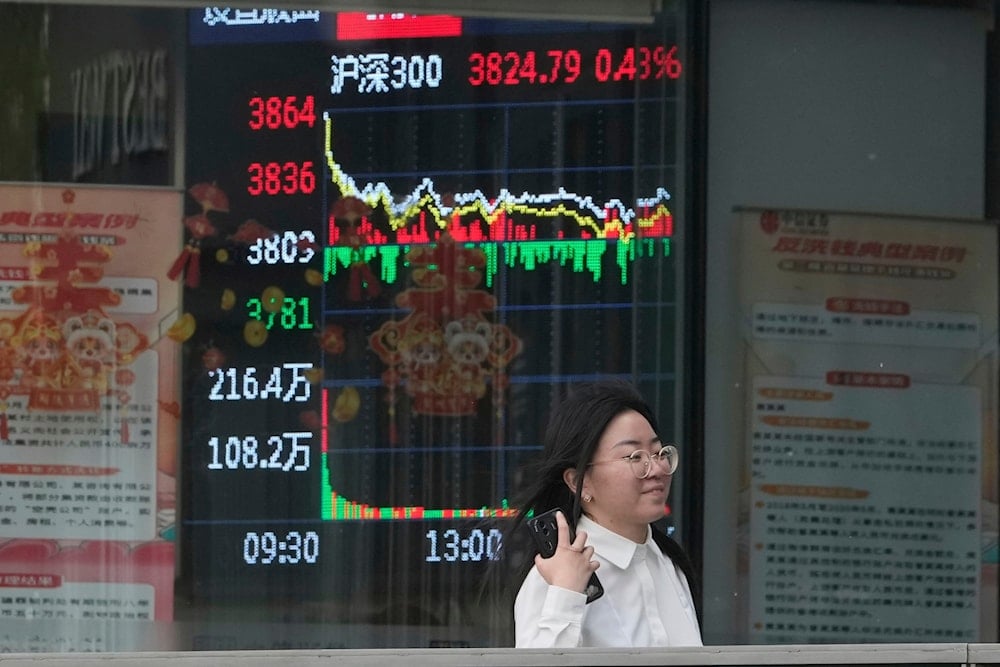 A woman passes by a stock index at a brokerage in Beijing, Wednesday, May 7, 2025 (AP)
