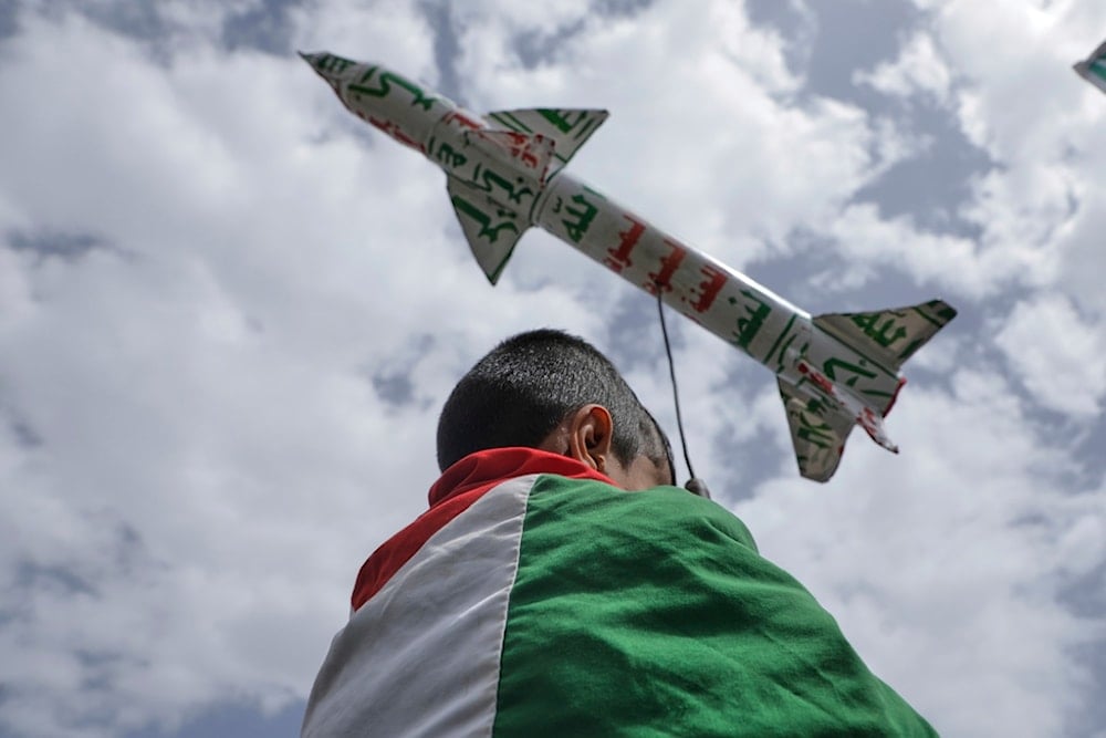 A boy draped in a Palestinian flag carries a mock rocket during a weekly anti-US and anti-Israeli rally in Sanaa, Yemen, Friday, May 9, 2025 (AP)