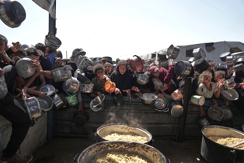 Palestinians struggle to obtain donated food at a community kitchen in Khan Younis, in the southern Gaza Strip, on May 9, 2025. (AP Photo/Abdel Kareem Hana)