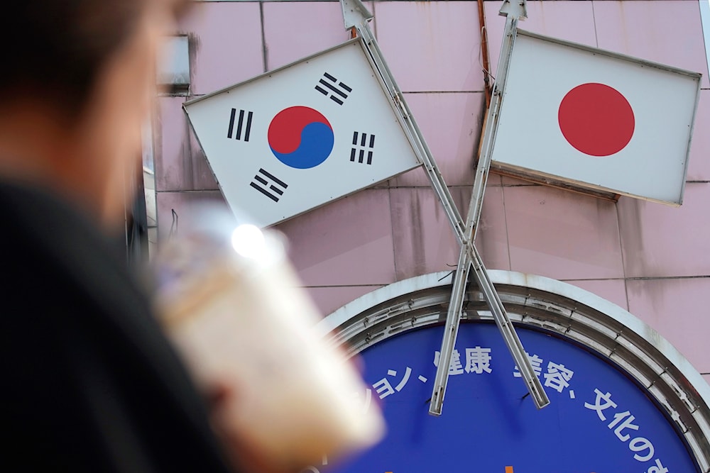 In this Aug. 2, 2019, file photo, a woman walks past an advertisement featuring Japanese and South Korean flags at a shop in Shin Okubo area in Tokyo. (AP)