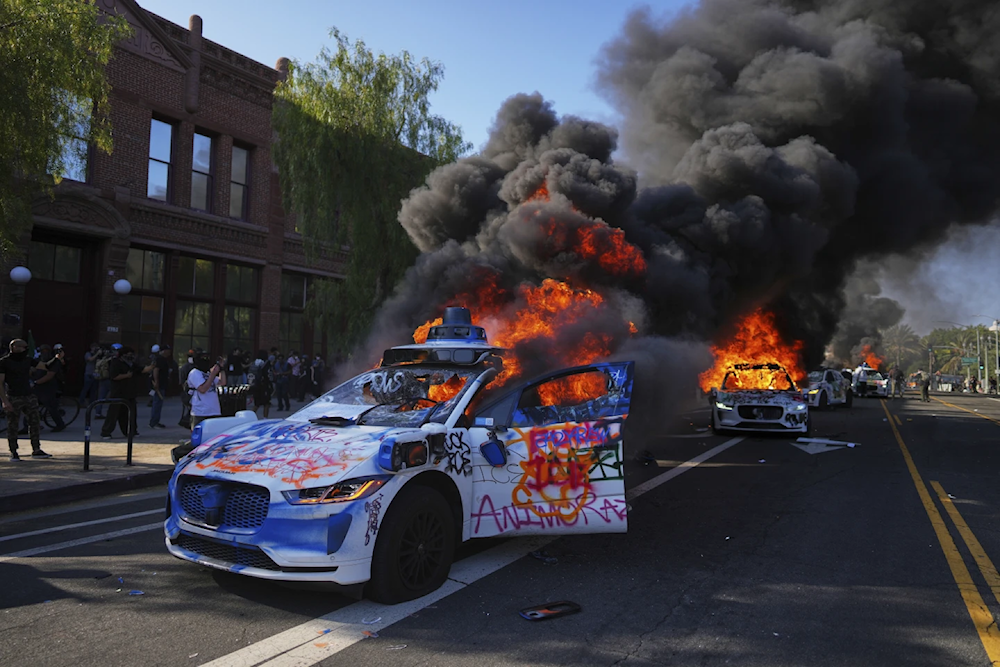 Multiple Waymo taxis burn near the Metropolitan Detention Center of downtown Los Angeles, June 8, 2025, following last night's immigration raid protest (AP/Eric Thayer)