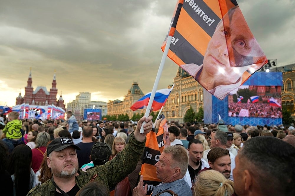 A man waves a flag with a portrait of Russian President Vladimir Putin as thousands gather on Red Square to watch a concert dedicated to the upcoming Day of Russia in Moscow, Russia, Wednesday, June 11, 2025 (AP)