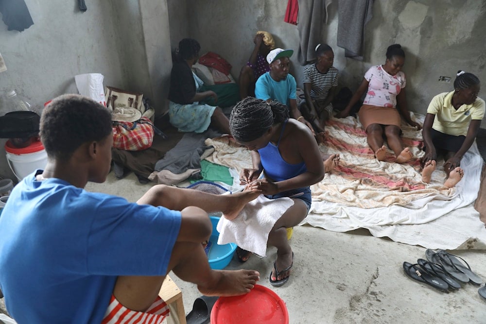 A woman gives a pedicure to a young man at a shelter for families displaced by gang violence in the Petion-Ville neighborhood of Port-au-Prince, Haiti, Saturday, April 26, 2025 (AP)