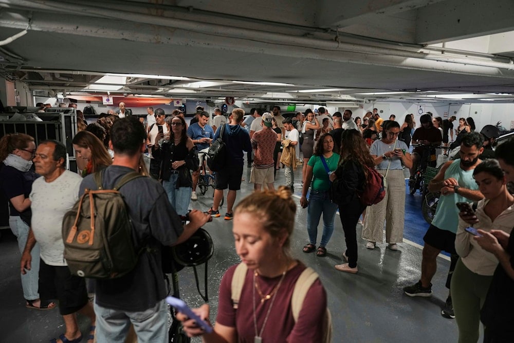 People take cover in an underground parking lot as a siren sounds a warning following a missile that was launched from Yemen, in Tel Aviv, Israel, Tuesday, May 13, 2025 (AP)