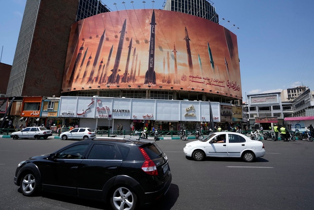Vehicles drive past an anti-Israeli banner showing missiles being launched, in a square in downtown Tehran, Iran, Friday, April 19, 2024. (AP)