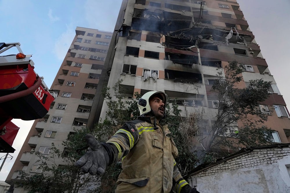 A firefighter calls out his colleagues at the scene of an explosion in a residence compound in northern Tehran, Iran, Friday, June 13, 2025 (AP)