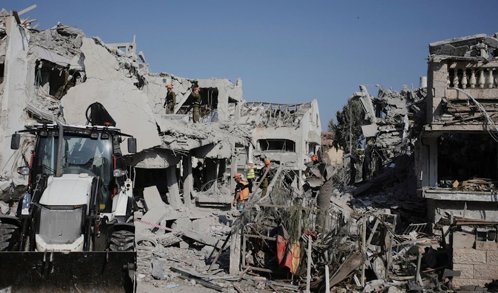 Israeli security forces inspect the site of homes destroyed by a missile fired from Iran, in Rishon Lezion, occupied Palestine, on Saturday, June 14, 2025. (AP)