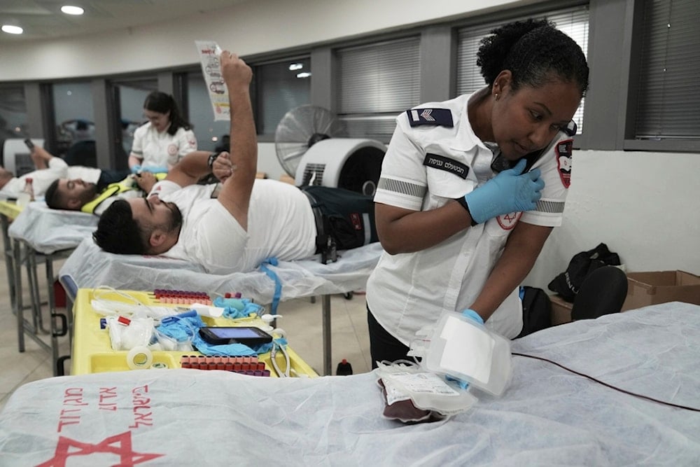 Medics with the Israeli Magen David Adom emergency service donate blood to prepare for mass casualties in the event of strikes by Iran, in occupied al-Quds, Saturday, June 14, 2025 (AP)