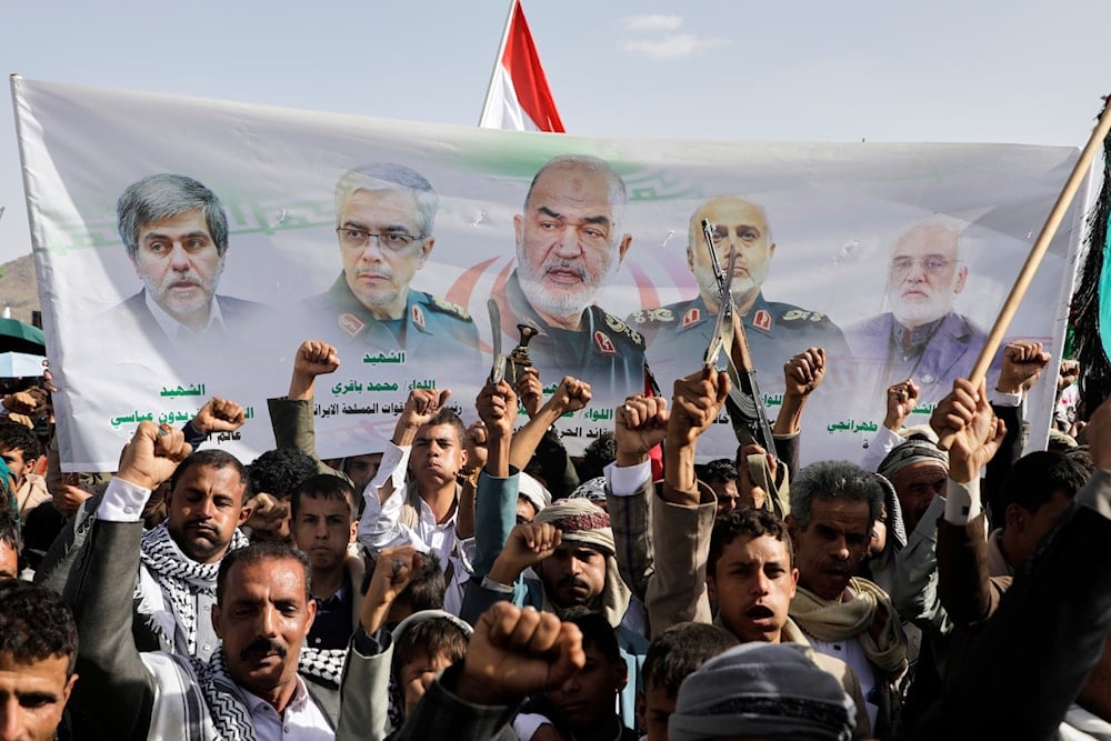 Ansar Allah supporters chant slogans as they raise a banner showing Iranian leaders who were killed during Israeli strikes, during a weekly anti-US and anti-