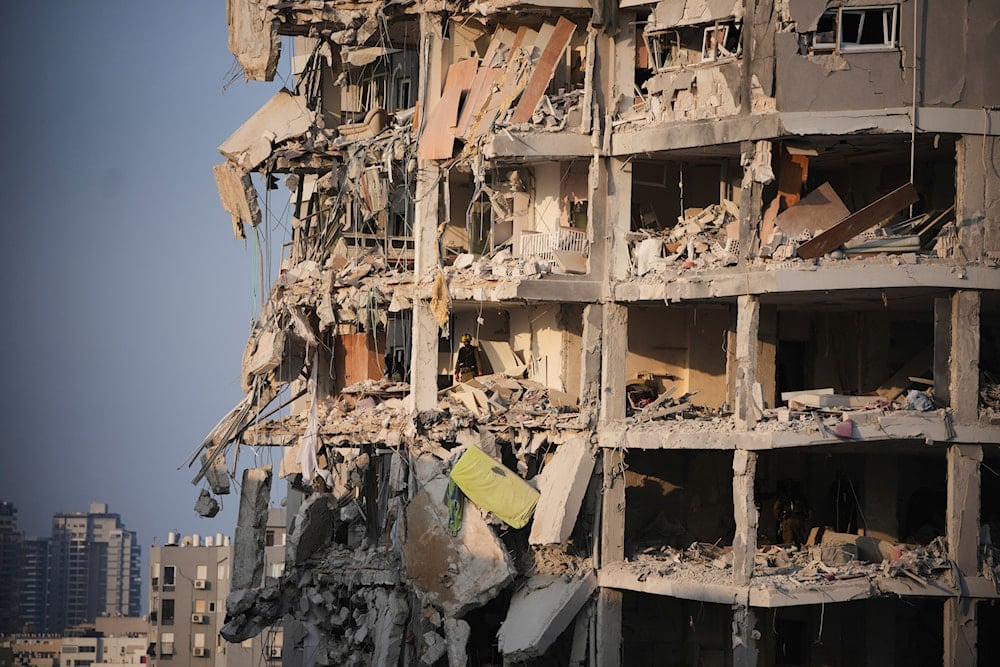 Israeli security forces inspect a destroyed building that was hit by a missile fired from Iran, near Tel Aviv, Occupied Palestine, Sunday, June 15, 2025 (AP)