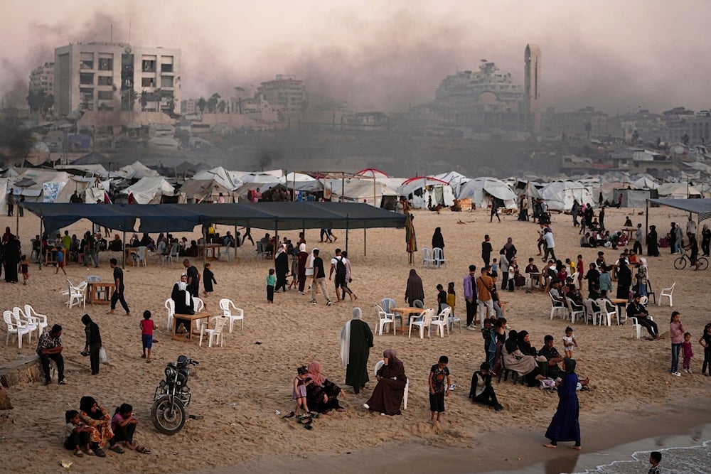 Palestinians spend time at the seafront next to a tent camp in the Gaza City port, Friday, June 13, 2025 (AP)