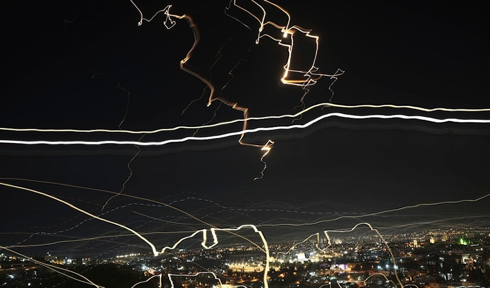 In this image taken with a slow shutter speed, missile projectiles light up the night sky over al-Quds during an Iranian missile attack, Friday, June 13, 2025. (AP)