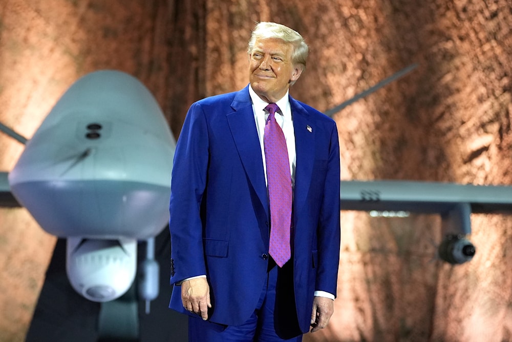 US President Donald Trump smiles backdropped by an MQ-9 Reaper drone before addressing military personnel at the Al Udeid Air Base, Thursday, May 15, 2025, in Doha, Qatar. (AP)