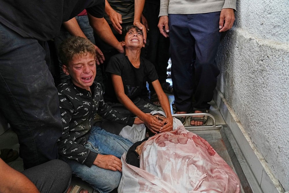 Palestinians children mourn over the body of their father, Mohammed Ghaben, who Israeli soldiers killed while heading to an aid distribution hub, at the morgue of the Shifa Hospital in Gaza City, Wednesday, June 18, 2025. (AP)