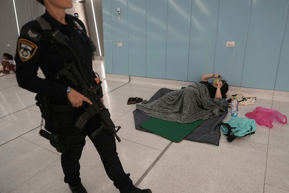 An Israeli police officer patrols as people take shelter in an underground metro station as a precaution against possible Iran missile attacks, in Ramat Gan, near Tel Aviv, Israel, Tuesday, June 17, 2025. (AP Photo/Oded Balilty)