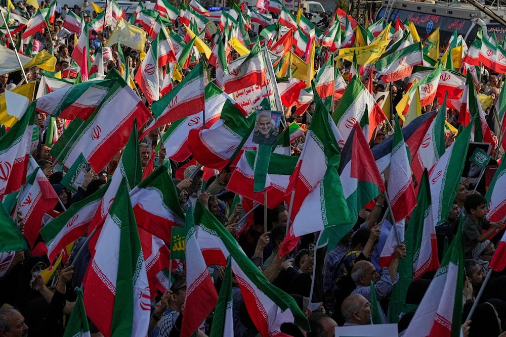 Demonstrators wave Iranian and Hezbollah flags as one holds a poster of the late Iranian Revolutionary Guard Gen. Qassem Soleimani, Tehran, Iran, June 14, 2025 (AP)(AP)