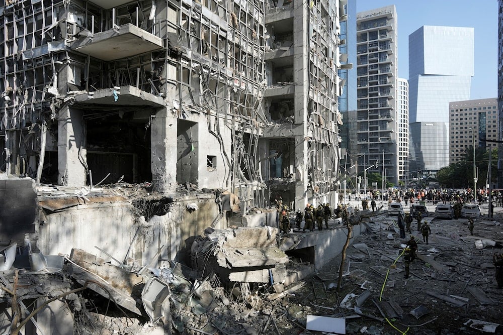 Rescue workers and military personnel inspect the site of a direct hit from an Iranian missile strike in Ramat Gan, occupied Palestine, on June 19, 2025. (AP Photo/Oded Balilty)