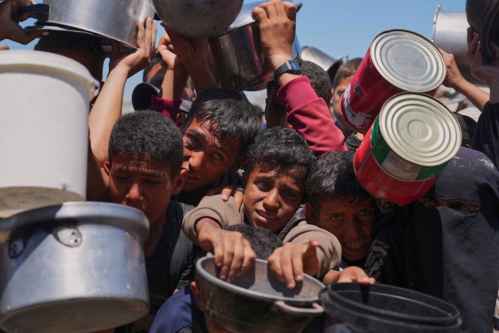 Palestinians struggle to get donated food at a community kitchen in Khan Younis, southern Gaza Strip, Monday, June 2, 2025 (AP)
