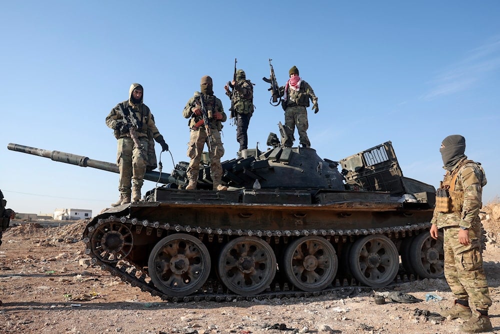 Syrian opposition fighters stand atop a seized Syrian army armoured vehicle in the outskirts of Hama, Syria, on December 3, 2024. (AP Photo/Ghaith Alsayed)