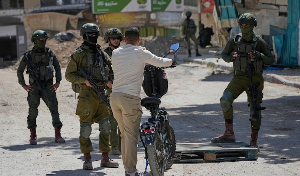 Israeli soldiers check the identification cards of residents of the now displaced Palestinian refugee camp of Tulkarm, May 29, 2025. (AP)