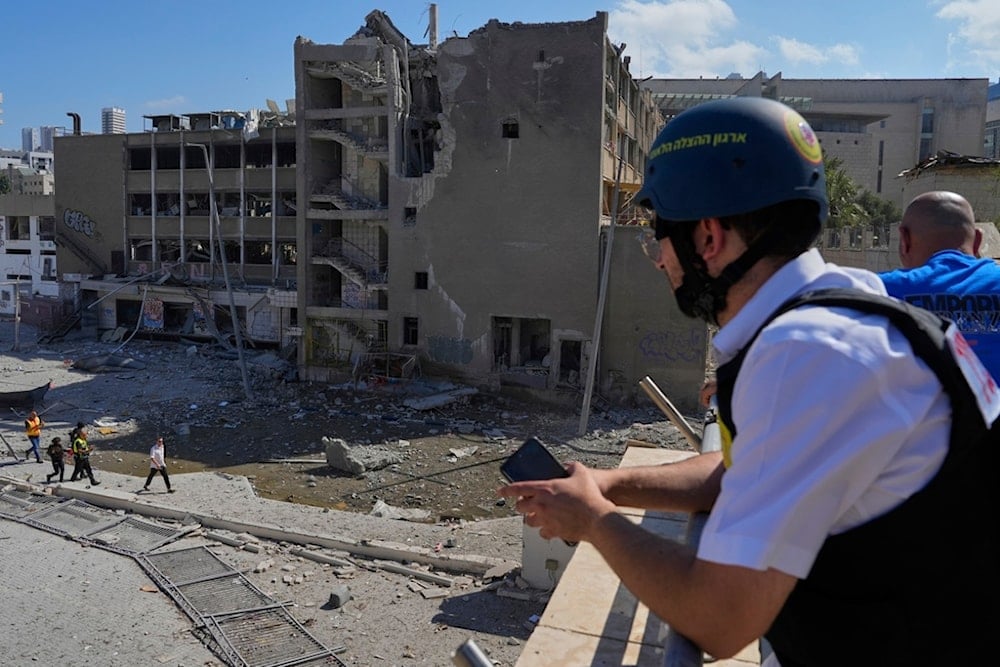 Israeli occupation forces and emergency teams work next to an unpopulated building after it was hit by a missile fired from Iran, in Haifa, occupied Palestine, Friday, June 20, 2025 (AP)