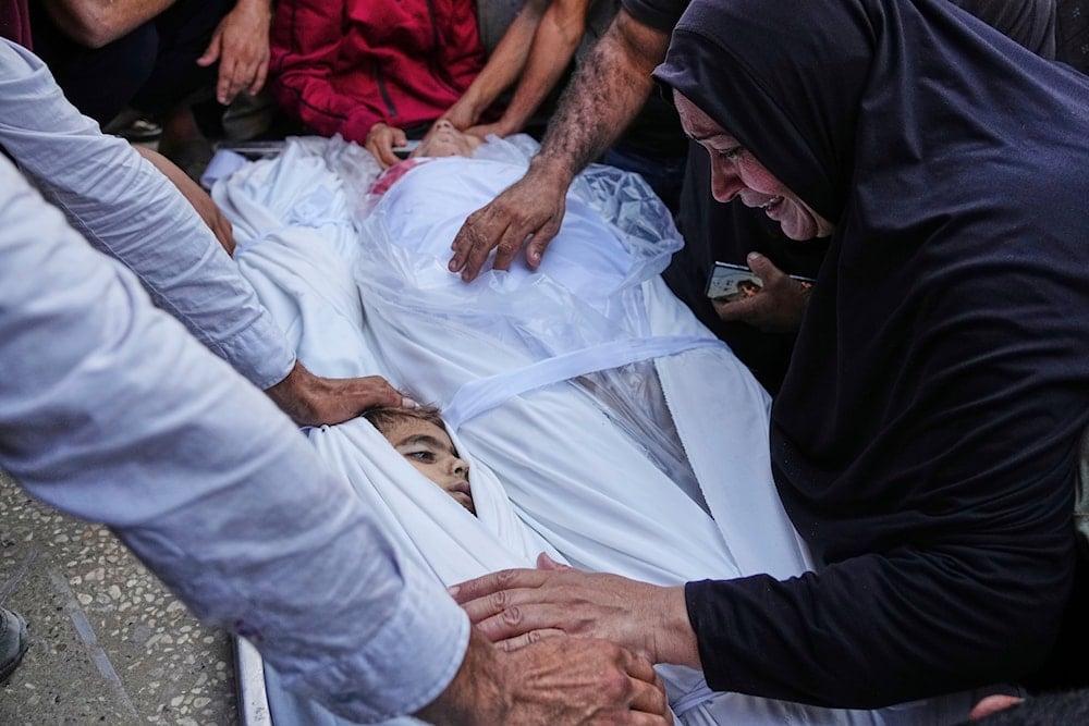 A Palestinian woman mourns over the body of a child who was killed in an Israeli military strike on Gaza, at Al-Shifa Hospital in Gaza City, Thursday, June 19, 2025 (AP)