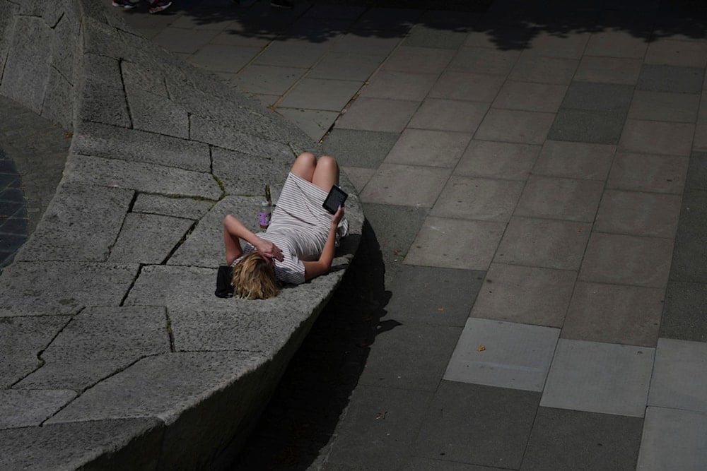 A woman lies in the sun in London, as a heatwave passes through the capital, Friday, June 20, 2025. (AP Photo/Kirsty Wigglesworth)