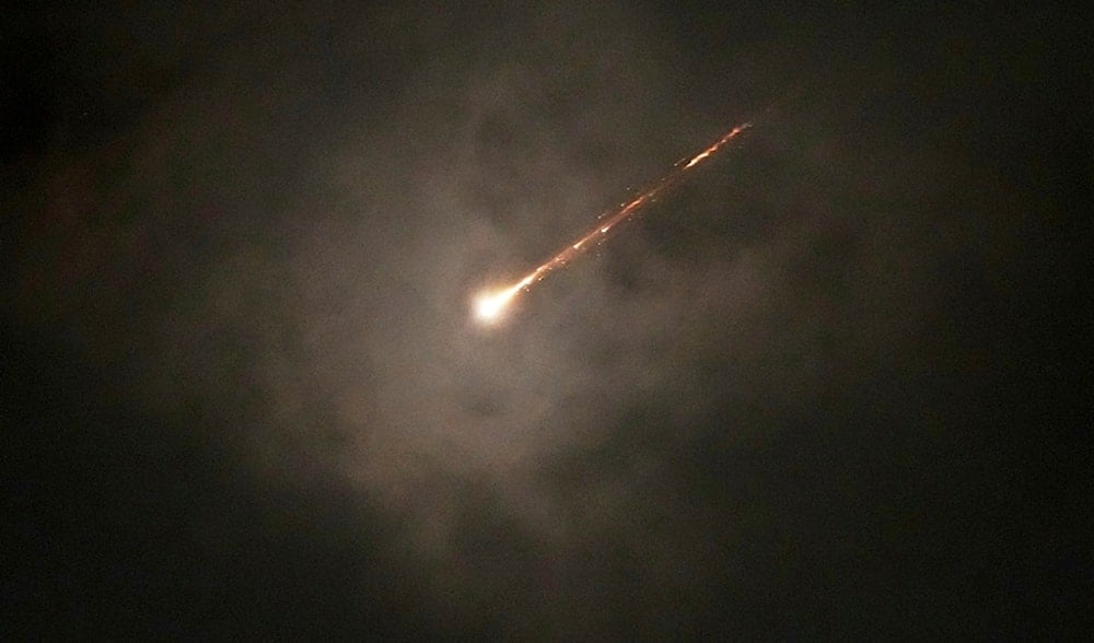 The trail of a projectile is seen through the clouds following a missile alert after launches from Iran, in al-Quds, early Monday, June 16, 2025. (AP)