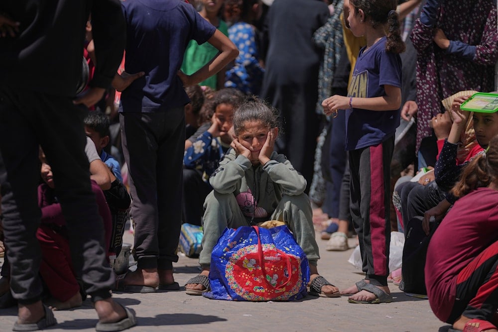 A Palestinian girl waits to collect donated food at a food distribution kitchen in Deir al-Balah, Gaza Strip, on May 30, 2025. (AP Photo/Abdel Kareem Hana)