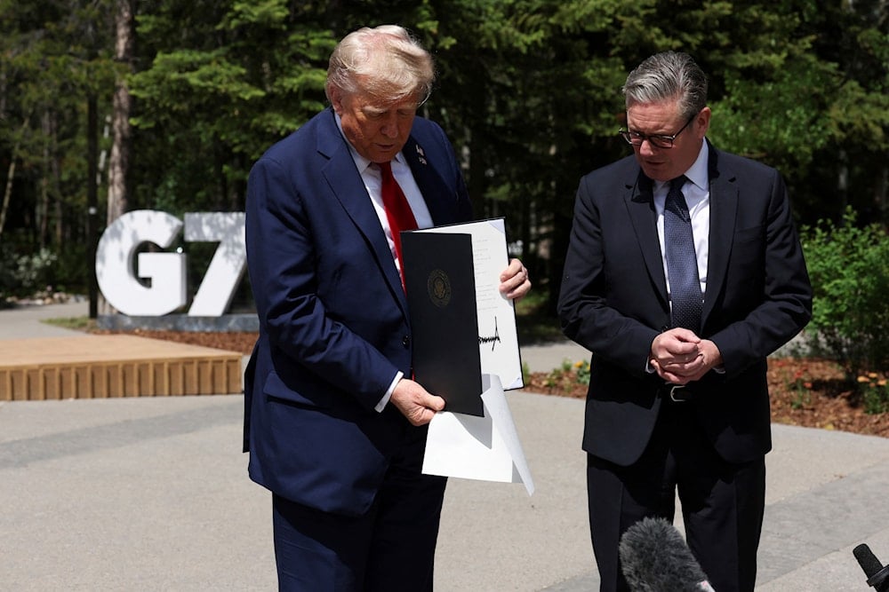 US President Donald Trump holds a signed UK-US trade agreement during a meeting with Britain's Prime Minister Keir Starmer, at the G7 summit, in Kananaskis, Alberta, Monday, June 16, 2025. (Suzanne Plunkett/Pool Photo via AP)
