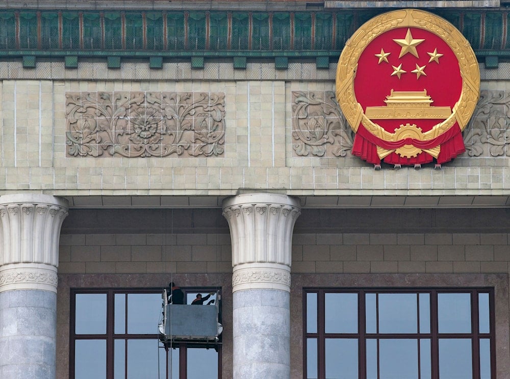 Workers clean the window glass near the Chinese national emblem outside the Great Hall of the People, preparing for the upcoming 18th National Congress in Beijing on November 2, 2012. 